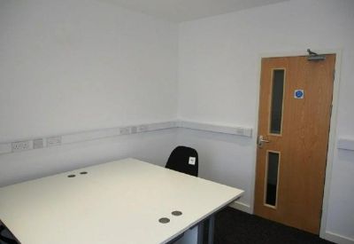 Private office space with a large white square desk and wooden door.