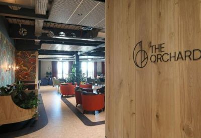 Wood-paneled lounge entrance with branded signage and red armchairs.