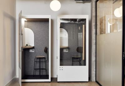 Sleek white acoustic phone booths with internal seating for private calls.