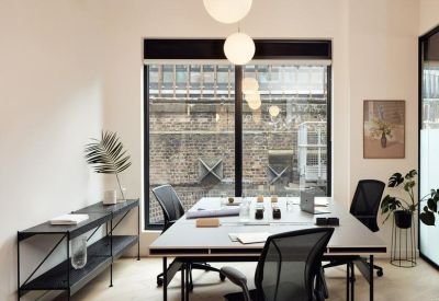 Private office space featuring a shared desk, adjustable chairs, and a window for natural light.