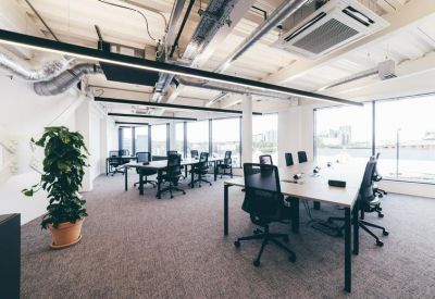 Professional office setup with long rows of desks and ergonomic black chairs.