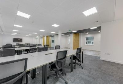 Open-plan office space with rows of grey desks and ergonomic chairs.