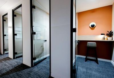 Private phone booths or focus rooms alongside a workstation with an orange wall.