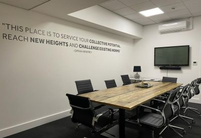 Modern meeting room featuring a wooden table and motivational wall text.