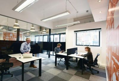 Bright open-plan office with white desks, ergonomic chairs, and large windows.