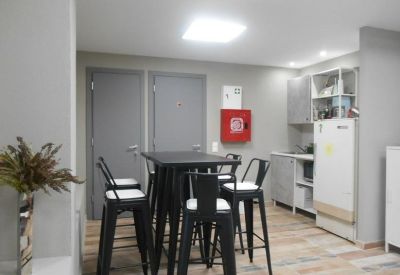 Communal kitchen and break area with high black stools and a white refrigerator.