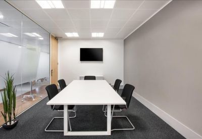 Modern meeting room with a white conference table, black chairs, and a wall-mounted TV.