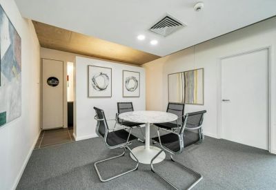 Private meeting room featuring a round white table, black chairs, and contemporary wall art.