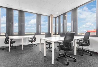 Bright corner office with four white desks and floor-to-ceiling windows.