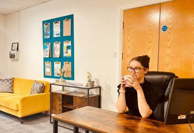 Reception desk area with a yellow sofa and a colorful clipboard display on the wall.