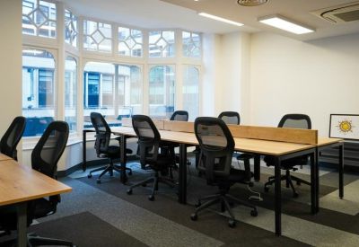 Open-plan workspace with rows of black mesh chairs and light wood desks.