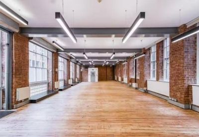 Large empty industrial office hall with exposed brick and modern linear lighting.