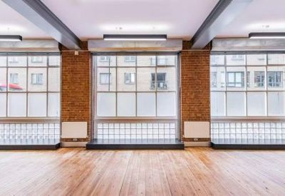 Spacious open-plan office featuring large multi-pane windows and brick pillars.