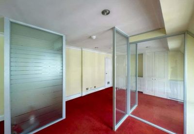 Private office space divided by glass partitions featuring vibrant red carpeting.