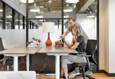 Collaborative meeting space with adjustable height desks, ergonomic chairs, and an orange desk lamp.