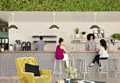 Modern office café with a geometric tile bar, green moss wall, and pendant lighting.