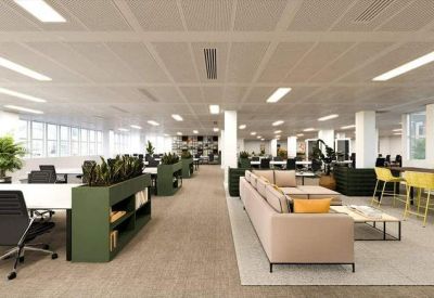 Bright communal lounge with a large beige sofa, yellow bar stools, and indoor plants.