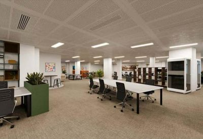 Spacious open-plan office featuring long white desks and black mesh ergonomic chairs.