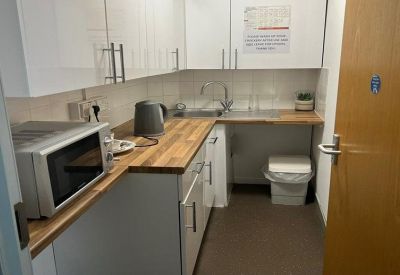 Modern communal kitchen with wooden countertops and white cabinetry.