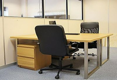 Private office suite with a wooden desk and black mesh chairs.