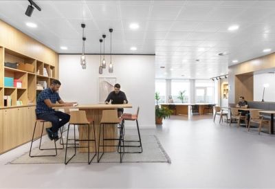 Meeting room with a large light-wood table, teal chairs, and built-in shelving.