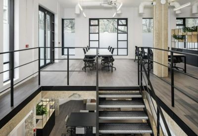 Mezzanine level workspace featuring a central staircase and long white workstations.