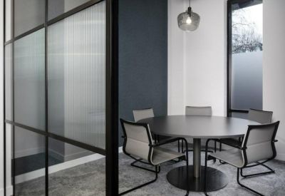Small meeting room with a round black table and mesh back chairs.