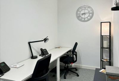 Private internal office with two workstations, a wall clock, and a floor lamp.