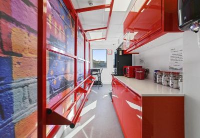 Sleek red kitchen area with modern cabinetry and a wall featuring vibrant graffiti art.
