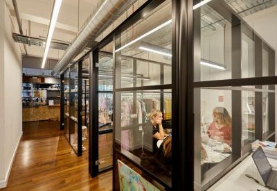 Glass-walled meeting rooms and offices along a polished wooden floor corridor.