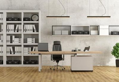 Minimalist office nook with a wooden desk, sleek black chair, and large white bookshelf.