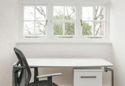 White desk with integrated storage set beneath a traditional sash window.