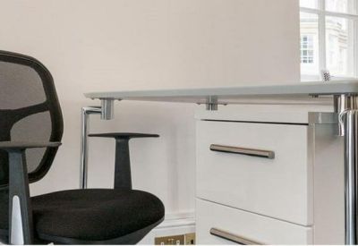 Close-up of a modern workstation with a grey mesh chair and white pedestal drawers.