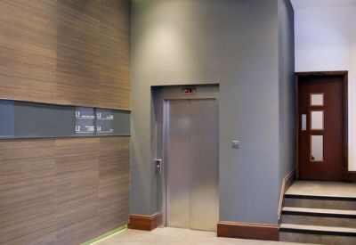 Modern reception lobby featuring wood paneling and a sleek silver elevator.