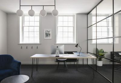 Private office suite with a minimalist desk and a black framed glass partition.