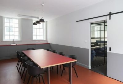 Meeting room with a long red table and a modern sliding barn door.