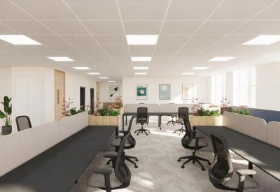 Spacious open office layout featuring ergonomic chairs and abundant ceiling light panels.
