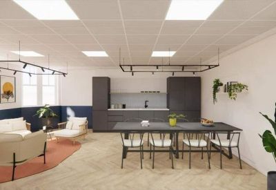 Communal kitchen and breakout area with a long dining table, grey cabinetry, and herringbone floors.