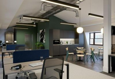 Open-plan office space featuring wooden desks, blue privacy screens, and a small breakout kitchen.