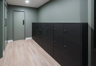 Sleek corridor lined with dark grey storage lockers and sage green walls.