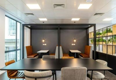 Sleek dining area with a long black table and private upholstered booths.