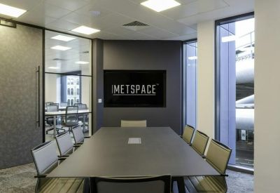 Modern meeting room featuring a grey table, leather chairs, and integrated video conferencing screen.