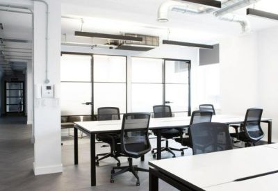 Open-plan office with white desks and black mesh chairs.
