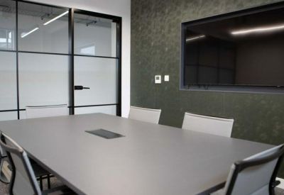 Modern meeting room with large table and wall-mounted screen.