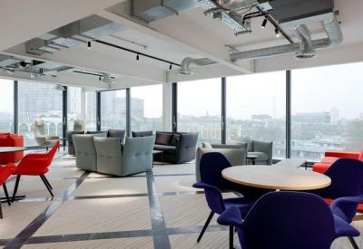 Sun-drenched breakout space with colourful chairs and floor-to-ceiling windows.