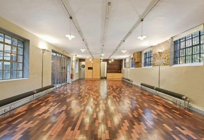 Long open-plan gallery space showing characterful wooden floors and multiple pendant lights.