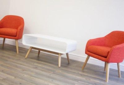 Breakout area with two vibrant orange armchairs and a minimalist white coffee table.