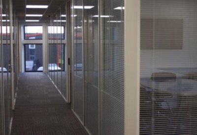 Bright office corridor with glass partitions and views of the industrial park.