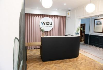 Branded reception area with a dark curved desk and pink curtain backdrop.