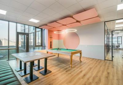 Game area with a pool table, wooden dining tables, and pink acoustic ceiling panels.